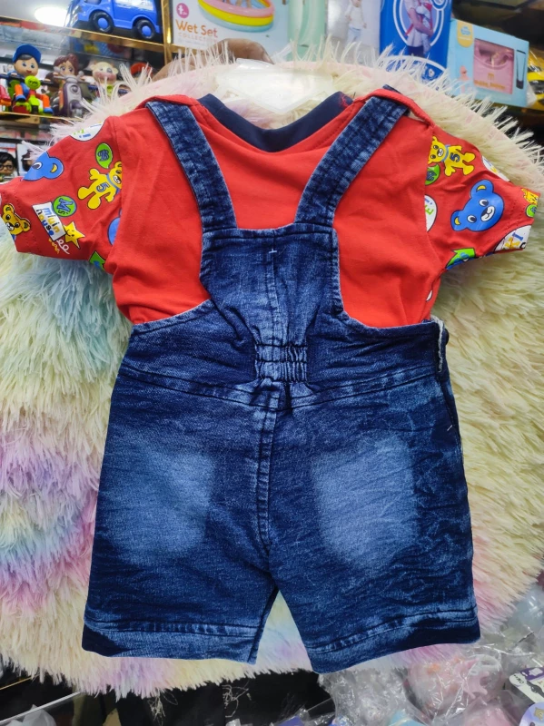 denim short-all dungaree paired with a red short-sleeved graphic t-shirt featuring a playful cartoon bear print